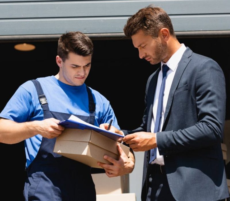 loader-holding-carton-box-while-businessman-in-sui-2023-11-27-05-02-36-utc-1024x684